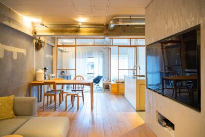 コンクリート壁と木製家具が調和した、開放的でモダンなワンルームの内観。